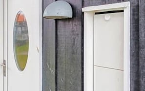 A door with a small window and a wall-mounted light fixture. - 4 Star Holiday Home in Bogense (Bogense)