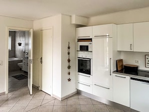A kitchen with white cabinets, a built-in oven, and a microwave. - 4 Star Holiday Home in Bogense (Bogense)