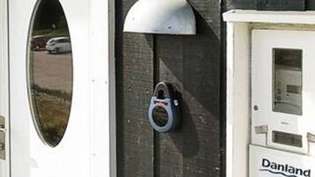 Une porte dotée d’une serrure métallique, une fenêtre donnant sur un parking et une enseigne Danland.