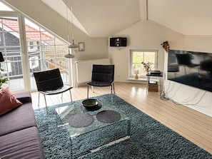A modern living room with a glass coffee table, two black chairs, a sofa, a TV, and a radiator. - 4 Star Holiday Home in Bogense (Bogense)
