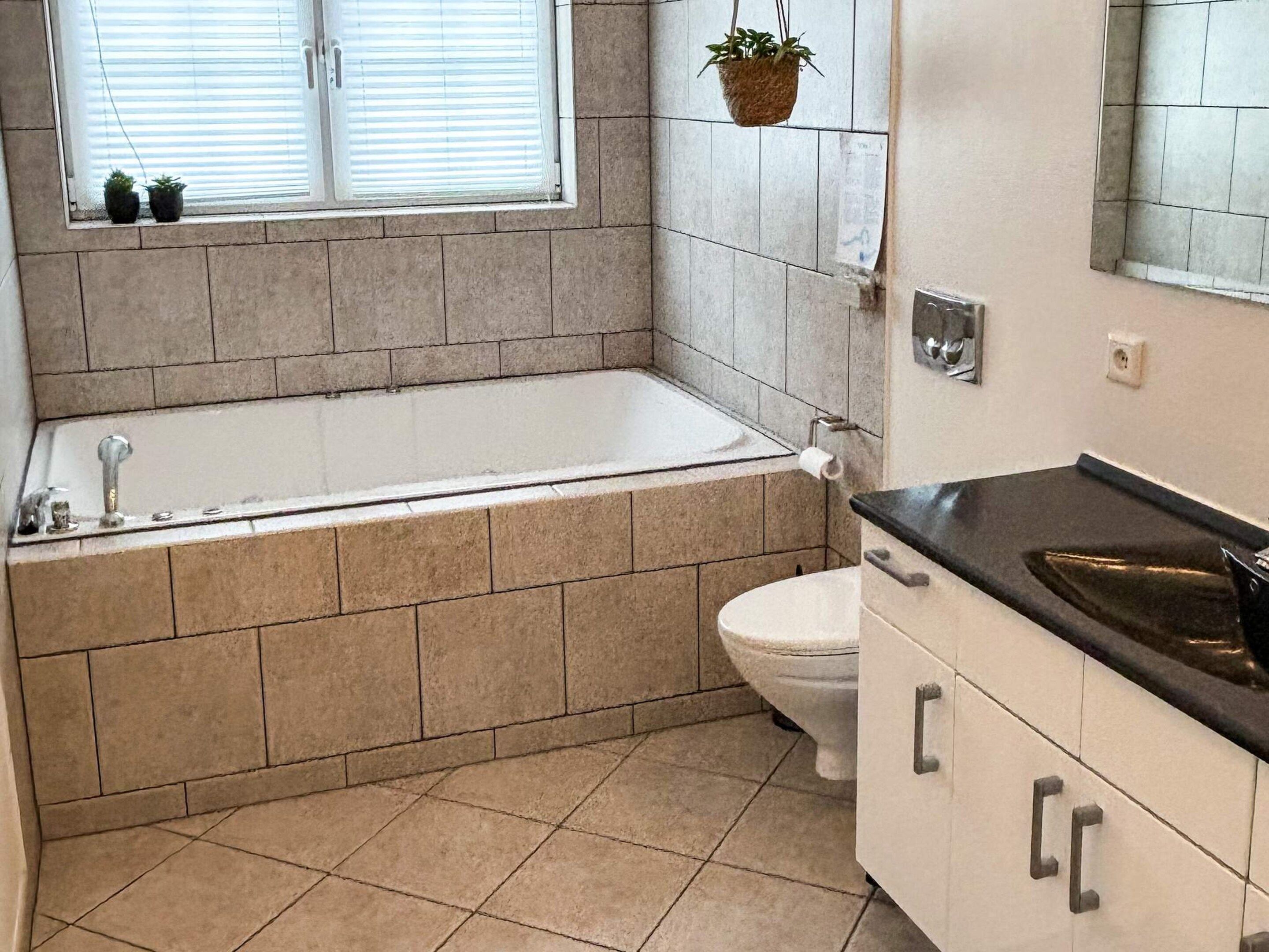 Een badkamer met een bad, toilet en wastafel.