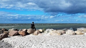 Un rivage rocheux où l’on voit une personne debout sur les rochers, surplombant la mer.