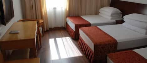 A hotel room with two beds, a wooden desk, a chair, and a TV.