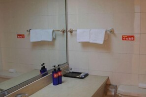 A bathroom with a mirror, two towels hanging on a towel rack, a sink with soap dispensers, and a trash bin. - Yandang Mountain Jinlaideng Hotel (Yueqing)