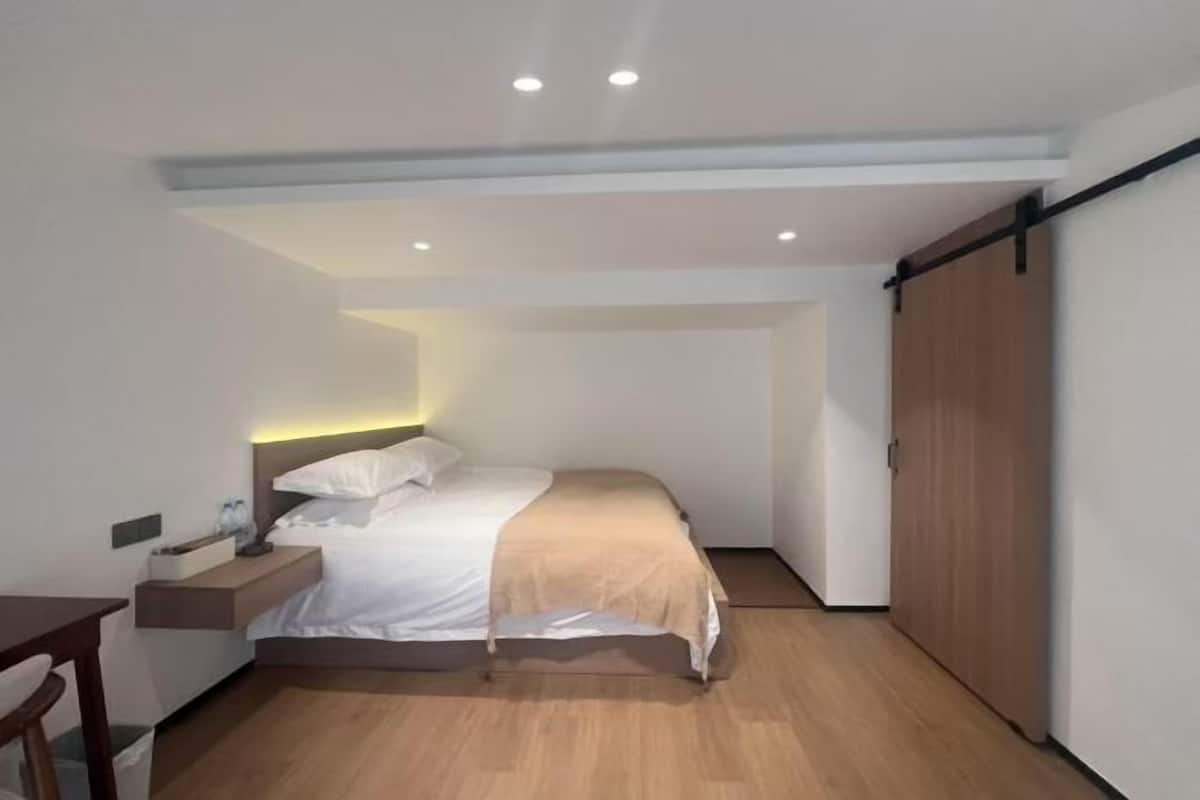 A modern bedroom with a bed, bedside table, and a wardrobe.