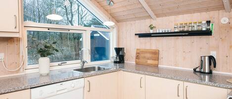 A modern kitchen with a dishwasher, sink, and coffee maker.