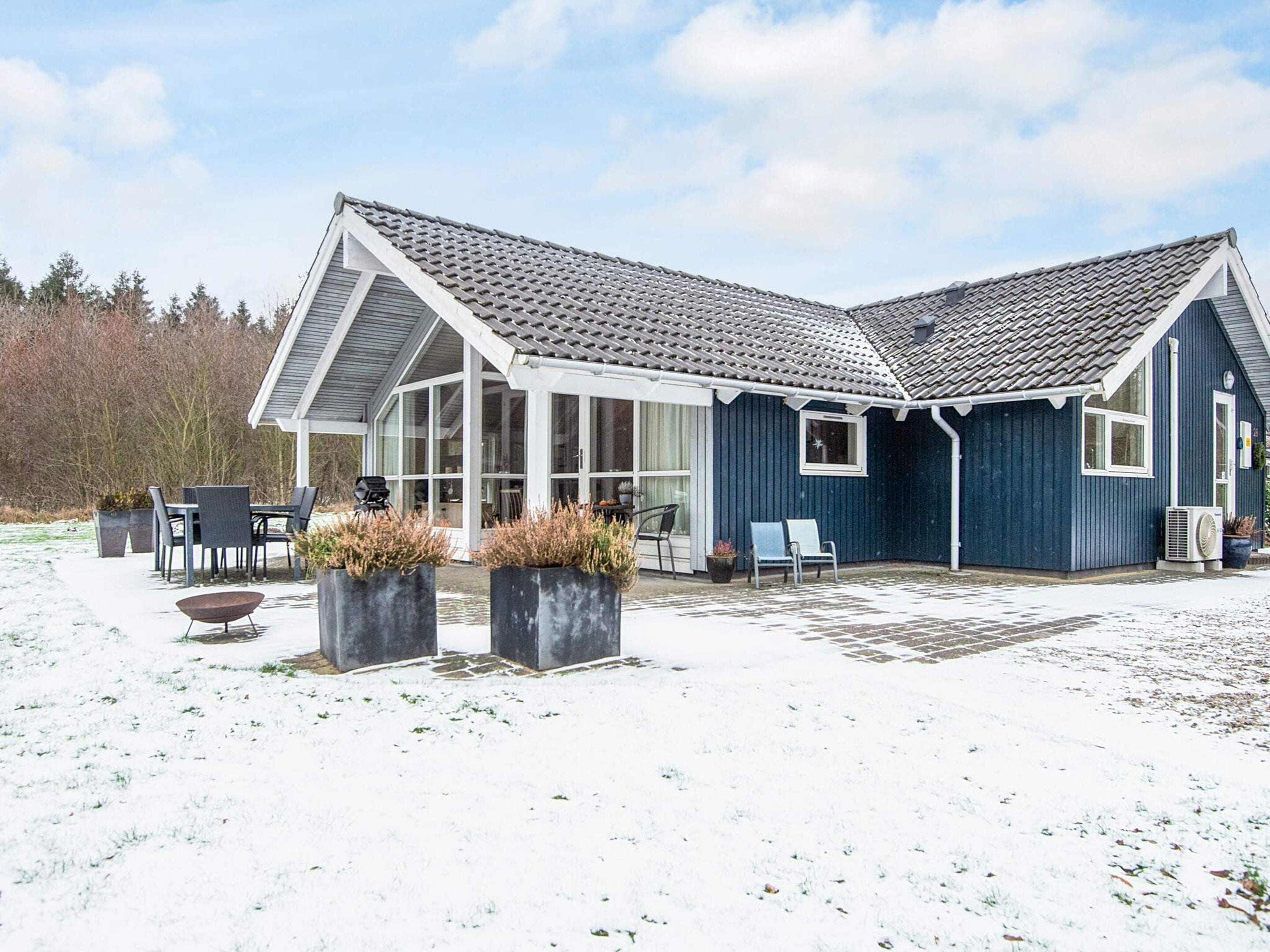A house with a large glass porch, outdoor seating, and a snow-covered yard.