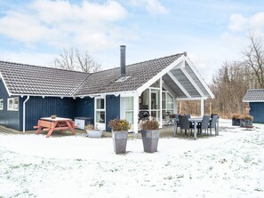 A house with a sloped roof, a chimney, and a covered patio area with outdoor furniture.