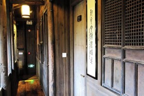 A narrow hallway with wooden walls and a door with a grid pattern. - Banshan Xianke Inn (Huangshan City)
