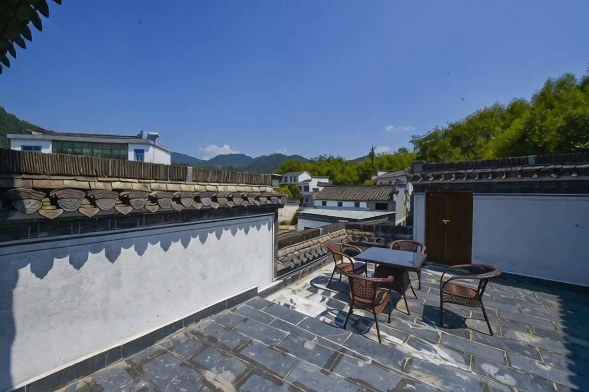 A traditional courtyard with tiled flooring, a table with chairs, and a view of surrounding buildings.
