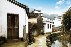 A narrow waterway flanked by traditional buildings with a wooden door and a small staircase leading to a higher level. - Banshan Xianke Inn (Huangshan City)