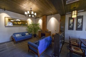 A room with a blue sofa, a wooden ceiling, a chandelier, and framed artwork on the walls. - Banshan Xianke Inn (Huangshan City)