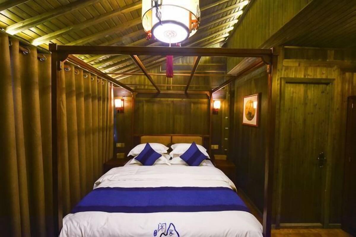 A room with a bed, wooden walls, a wooden ceiling, and a door.