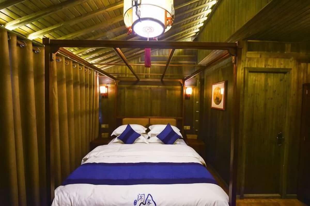 A room with a bed, wooden walls, a wooden ceiling, and a door.