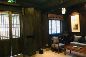 A traditional room with wooden walls, a sofa, a chair, a table, and a window with a view. - Banshan Xianke Inn (Huangshan City)