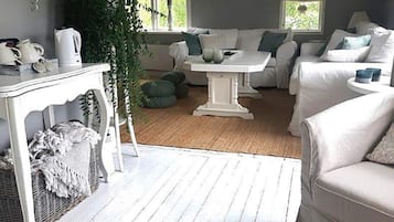 Una sala acogedora con un sofá blanco, una mesa de centro de madera y una mesa de comedor con sillas.