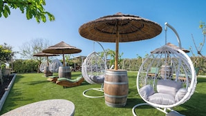 Outdoor seating areas with hanging chairs and thatched umbrellas, surrounded by greenery.