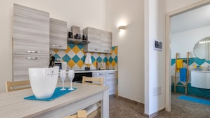 A modern kitchen with a dining area, featuring a table with two white cups, a microwave, and a toaster.