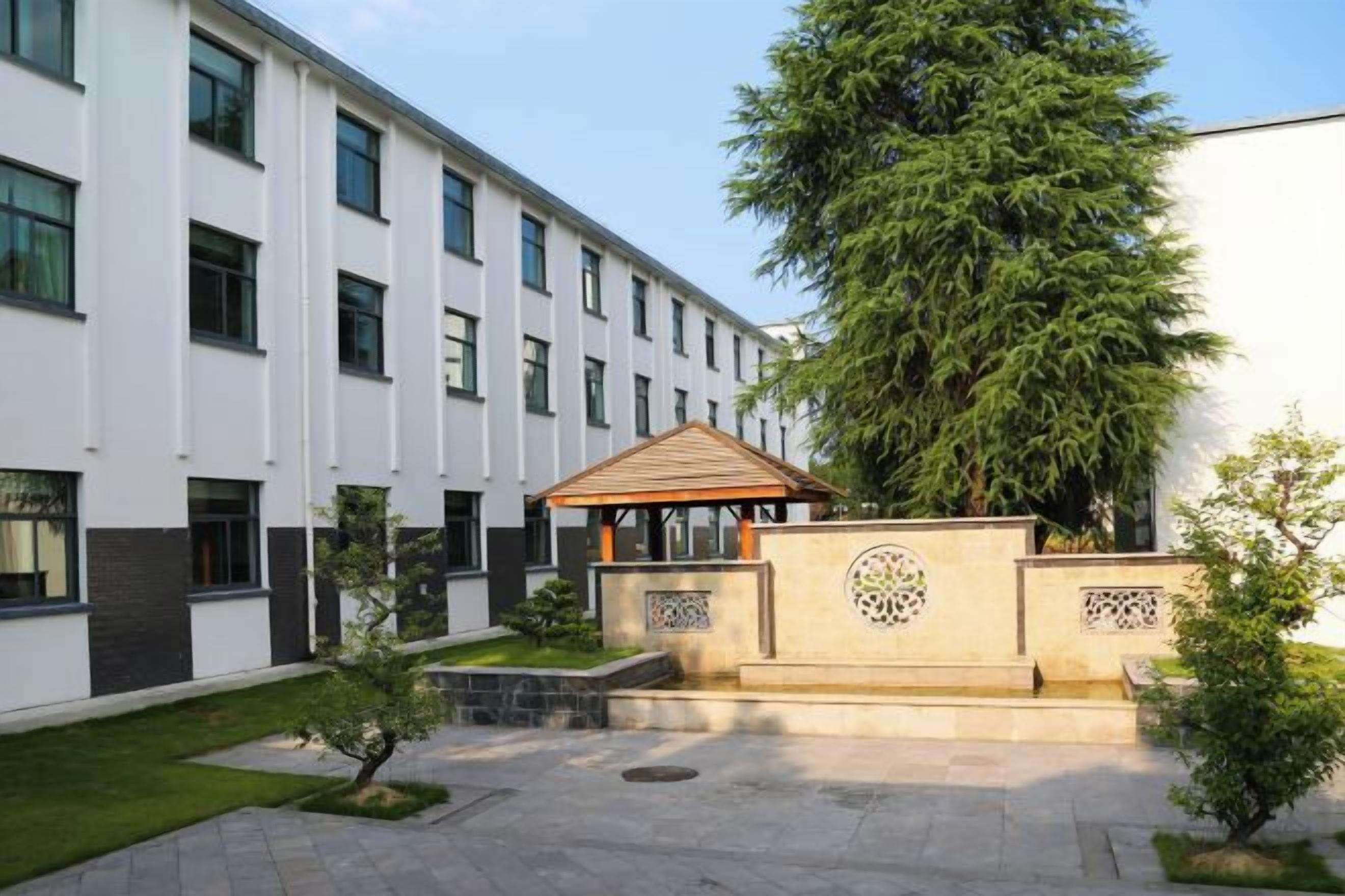 A courtyard with a gazebo, a large tree, and a building with multiple windows.
