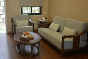 A living room with a sofa, armchairs, a coffee table, and a window with blinds. - Welcome Song Hotel (Huangshan City)
