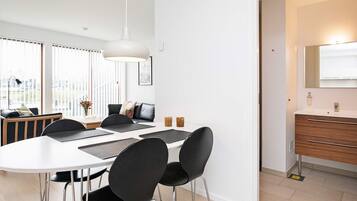 Un comedor moderno con una mesa blanca, sillas negras y una lámpara colgante.