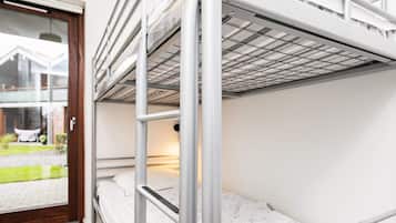 A bunk bed with metal railings, a window with a view of a house, and a door.