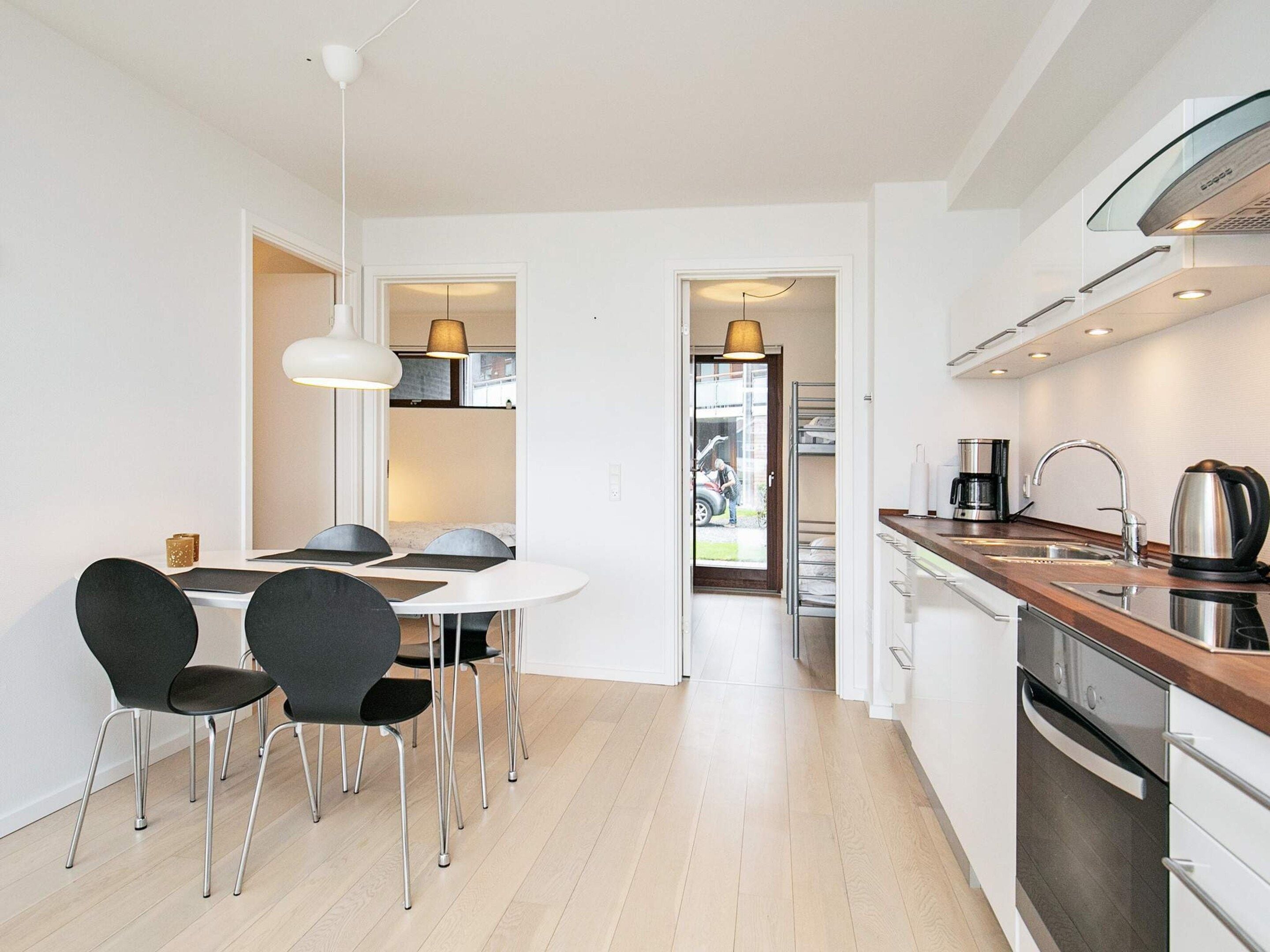 Une cuisine moderne avec un coin repas, un four encastré et une vue sur la rue.