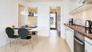 A modern kitchen with a dining area, a built-in oven, and a view of the street. - 4 Star Holiday Home in Bogense (Bogense)