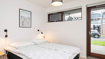 Un dormitorio con cama, lámparas de noche, una ventana y un cuadro en la pared.