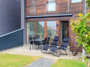A patio with a table and chairs, a wooden deck, and a brick pathway.