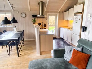 A modern kitchen with a central island, wooden flooring, and a dining area with a table and chairs.