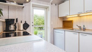 A modern kitchen with a glass countertop, white cabinets, and a built-in dishwasher. - 6 Person Holiday Home in Juelsminde (Horsens)