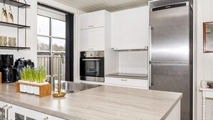 A modern kitchen with white cabinetry, a stainless steel refrigerator, and a built-in oven. - 6 Person Holiday Home in Logstor (Logstor)