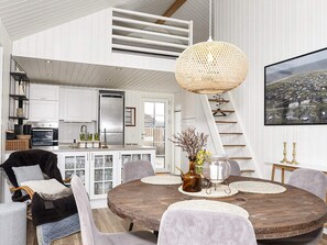 A modern kitchen with white cabinetry, a large island, and a hanging woven light fixture.