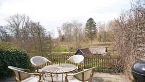 An outdoor patio with wicker chairs and a round table, surrounded by a wooden fence and trees. - 2 Person Holiday Home in Aakirkeby (Akirkeby)