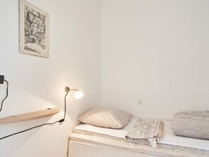 A bedroom with a single bed, a bedside lamp, a wall-mounted shelf, and a framed picture. - 2 Person Holiday Home in Aakirkeby (Akirkeby)