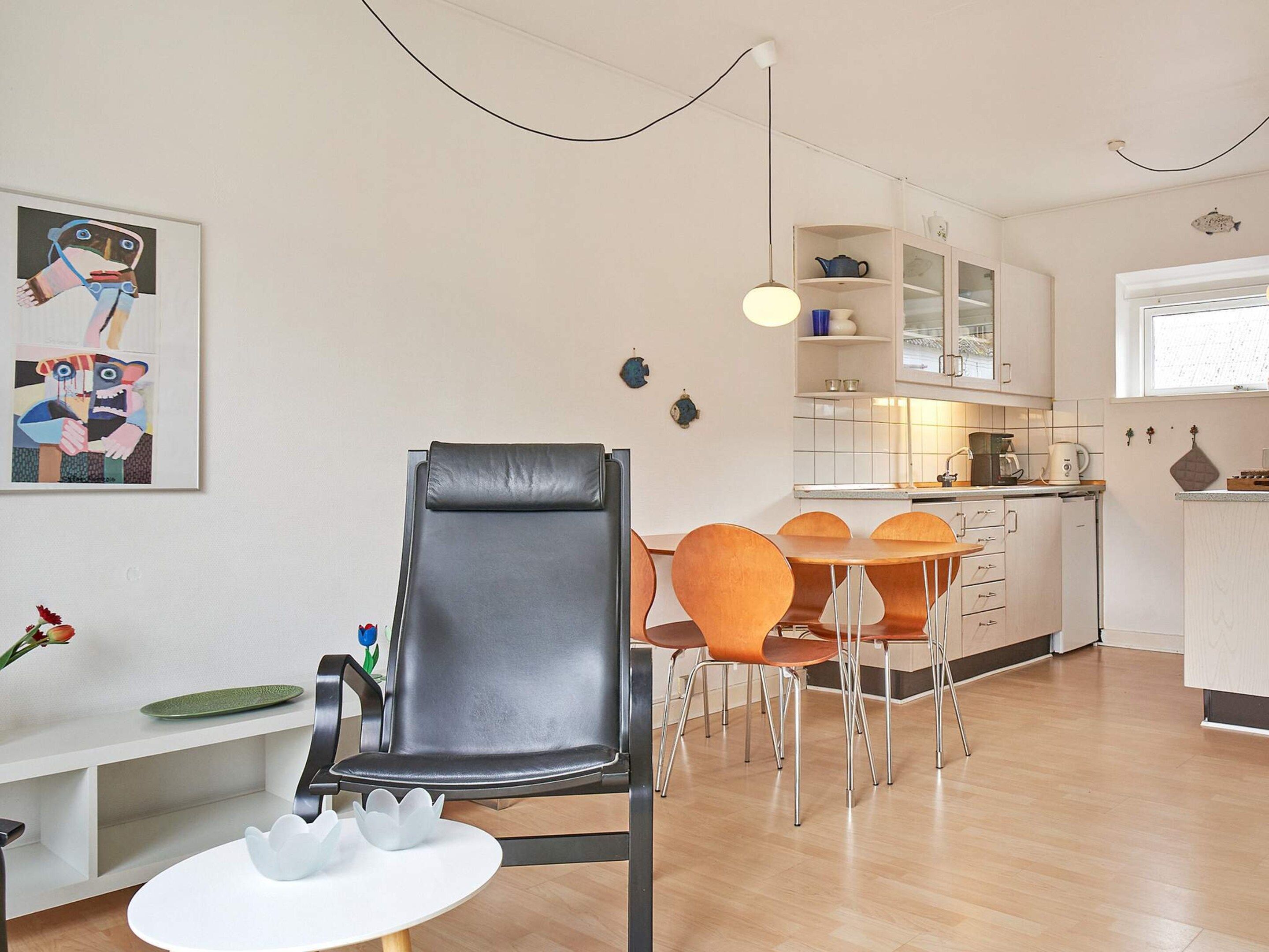 A modern living space with a dining area, kitchen, and a painting on the wall.