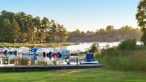 A marina with boats docked, a grassy area in the foreground, and trees in the background.