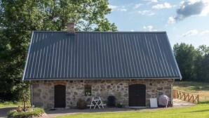 A stone building with a metal roof, two doors, and a small porch area. - 4 Star Holiday Home in Simlangsdalen (Simlangsdalen)