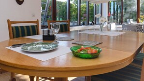 A dining area with a wooden table, chairs, a bowl of salad, and a wine glass. - 12 Person Holiday Home in Idestrup (Idestrup)