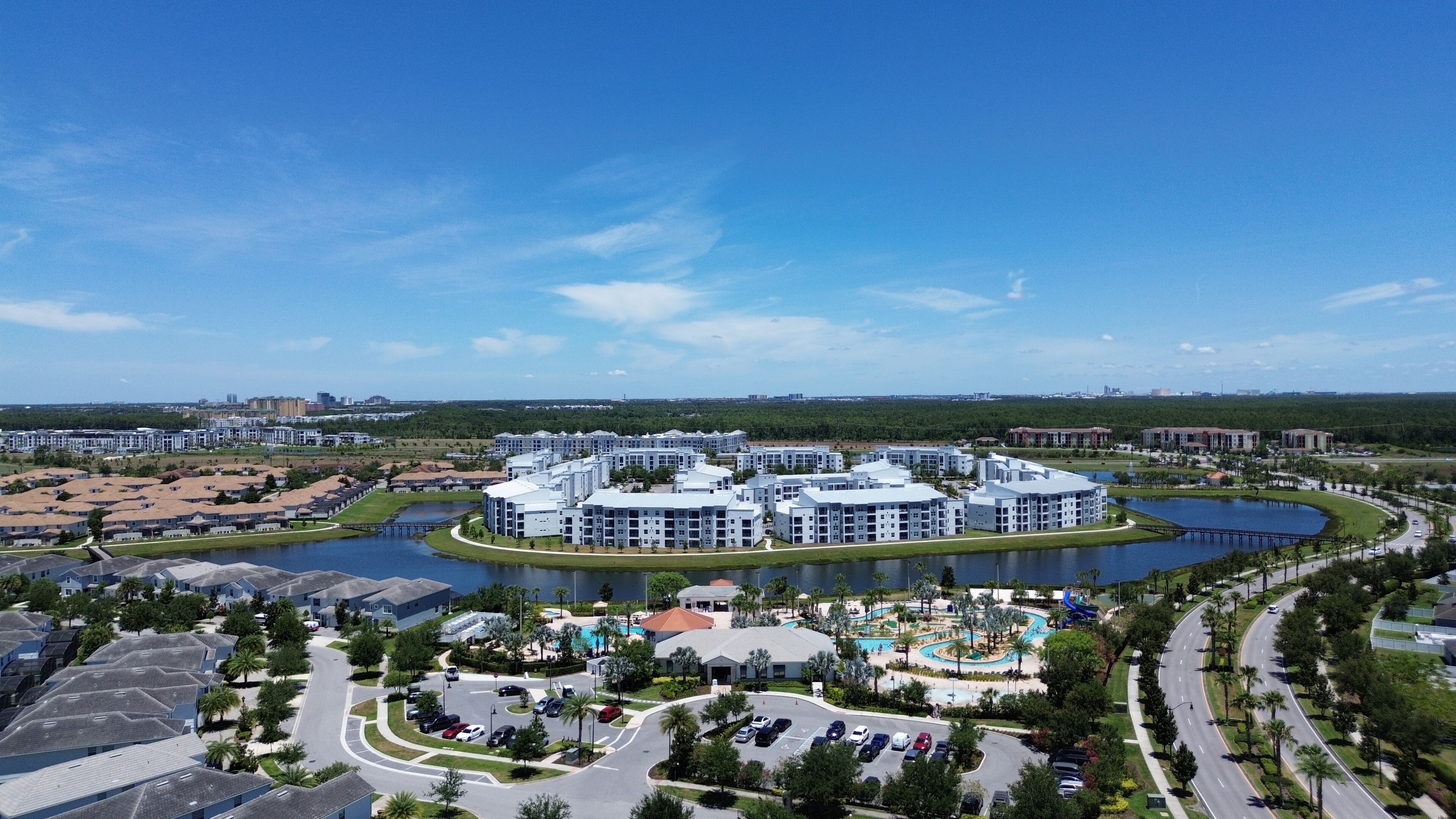 A modern residential complex with multiple buildings, a central courtyard with a swimming pool, and a lake.