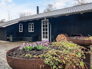Rakennuksessa on tumma julkisivu, savupiippu ja lasiruutukuvioitu ovi.
