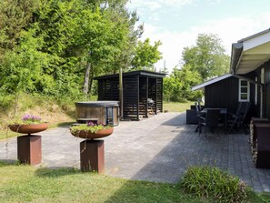 Een terras met tuinmeubilair, een jacuzzi en een houten constructie.