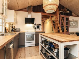A compact kitchen with a wooden countertop, stainless steel appliances, and a hanging light fixture.