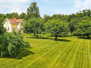 A yellow building with a red roof, surrounded by a well-maintained lawn and several trees. - 4 Star Holiday Home in Nykvarn (Nykvarn)