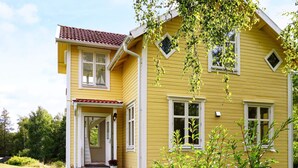 A yellow two-story house with a front porch, a red-tiled roof, and a small garden area. - 4 Star Holiday Home in Nykvarn (Nykvarn)