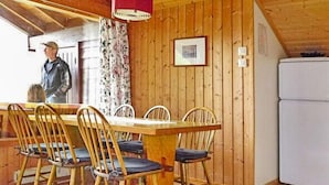 A wooden-paneled room with a dining table, chairs, a refrigerator, and a window with curtains. - 6 Person Holiday Home in Olden (Stryn)