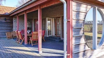 A covered patio with wooden furniture and a large window.