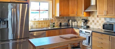 A modern kitchen with stainless steel appliances, wooden cabinets, and a central island with a sink.