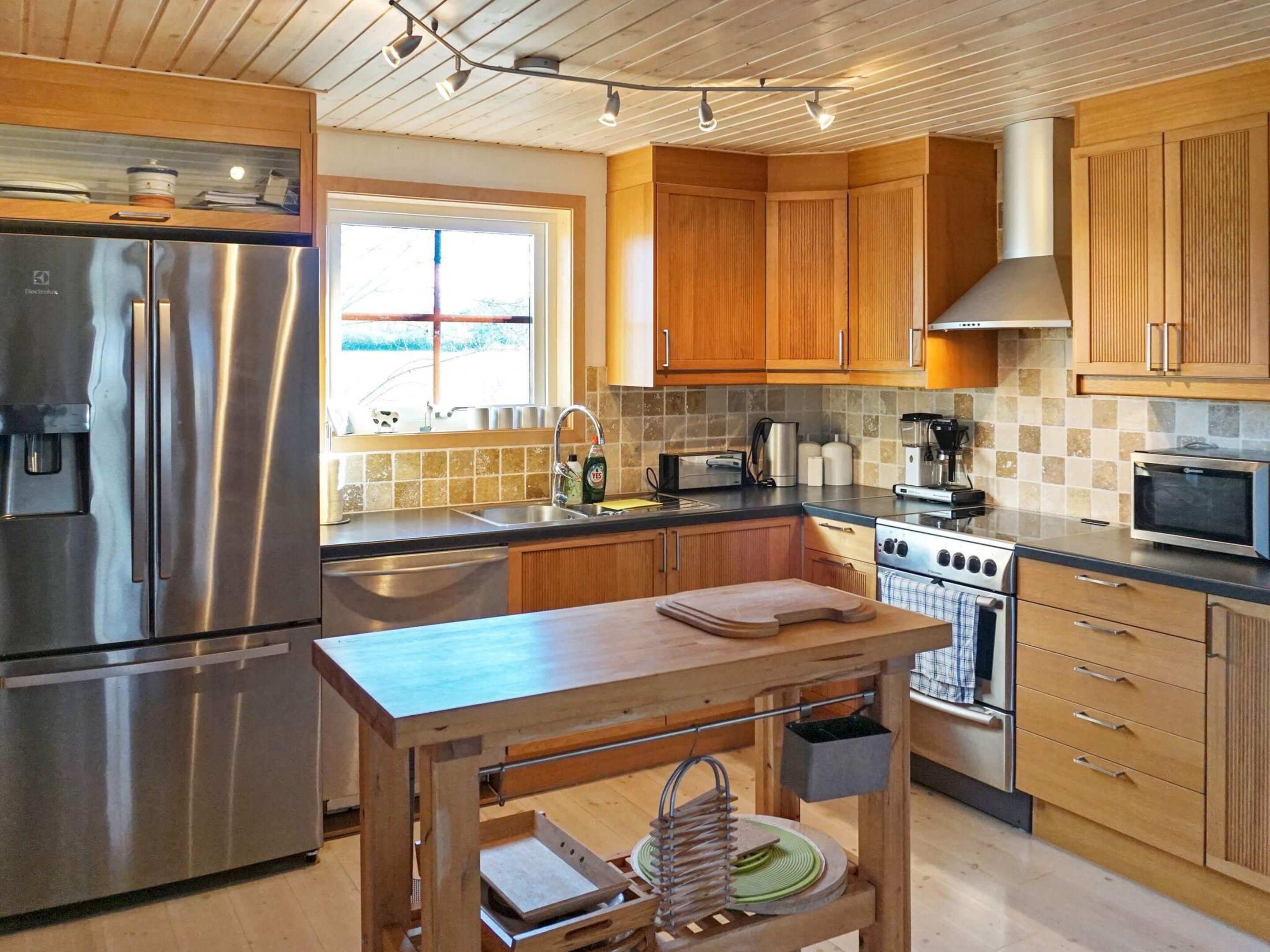 A modern kitchen with stainless steel appliances, wooden cabinets, and a central island with a sink and storage.